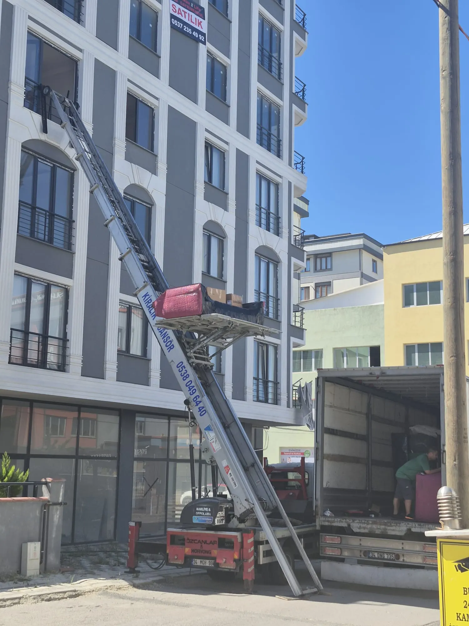 Apartman önünde nakliye kamyonu ile birlikte çalışan mobilya asansörü